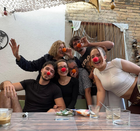 Grup d'amics en un sopar fent-se una foto amb nassos vermells de pallasso