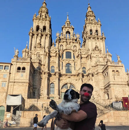 Persona amb nas vermell i el seu gos davant la catedral de Santiago de Compostel·la